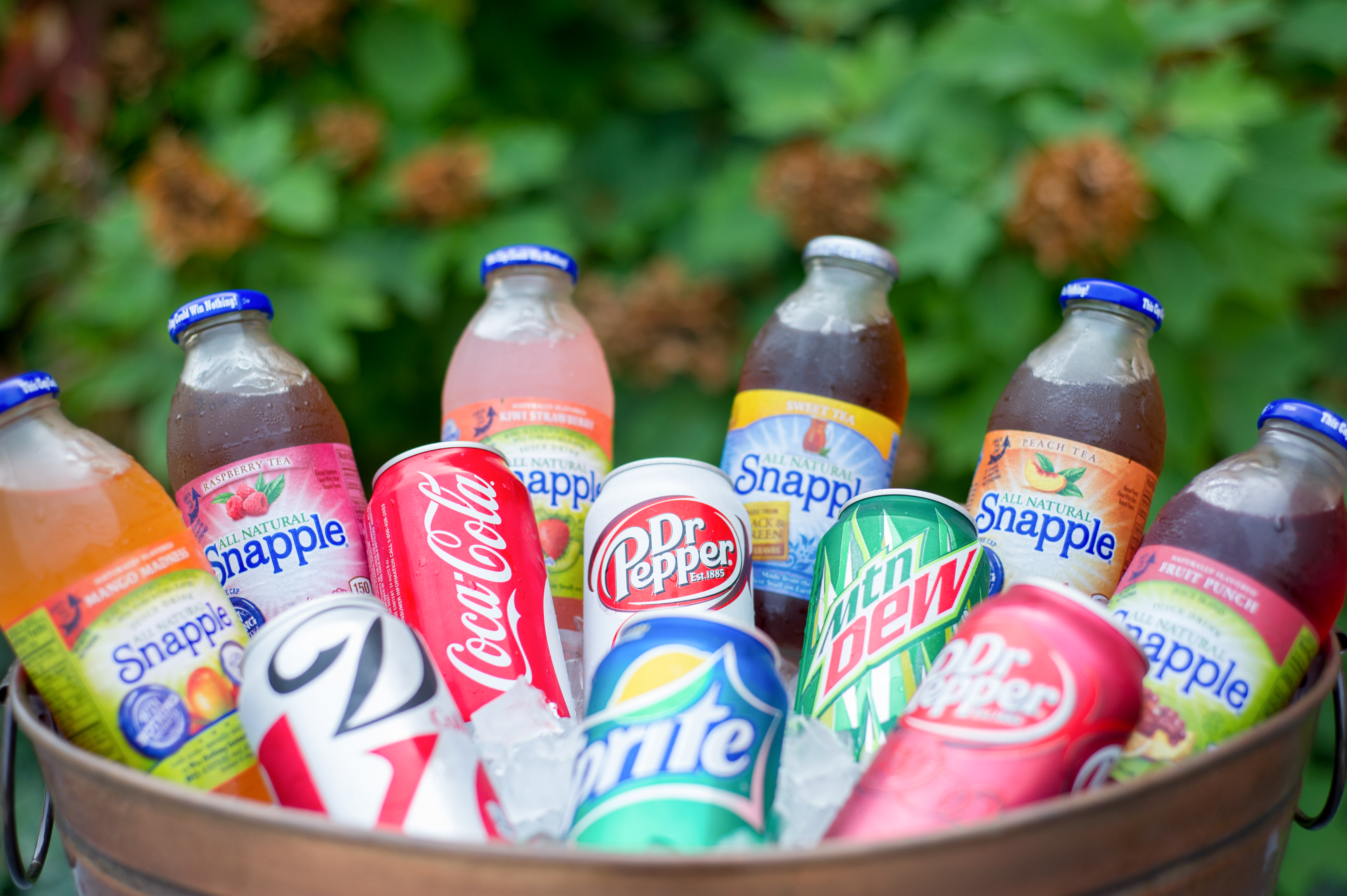 assorted bottles of snapple drink displayed in a bucket of ice